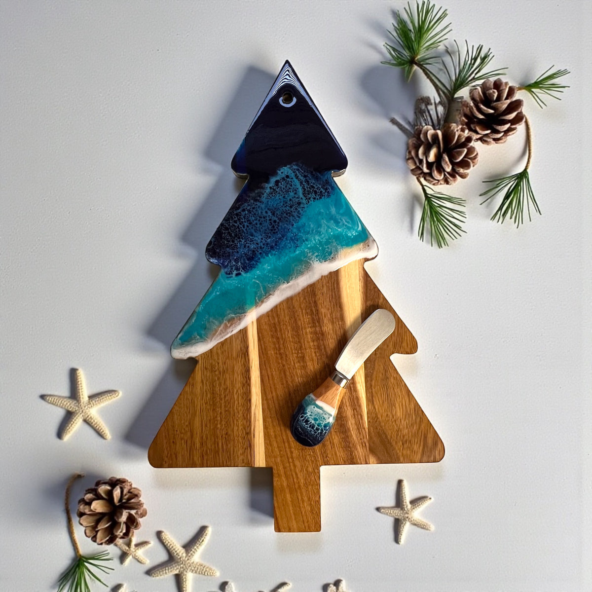 Daphnew Design Christmas tree shaped acacia wood cheese board with blue ocean resin art and matching cheese knife.